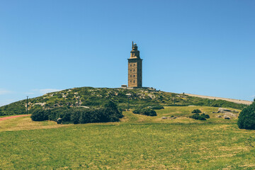 Old tower Hercules lighthouse over green field in A Coruña 