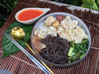 Black noodles with seafood and tofu meatball in red soup 