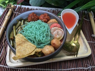 Green noodles konjac with seafood and tofu meatball in red soup 