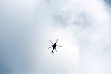 Helicopter flying in cloudy sky. Silhouette of helicopter against sky