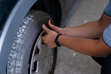 Auto mechanic working removing a hubcap from a car wheel in a garage.