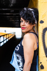 Mid adult afro mexican woman leaning against a wall at the entrance of a tunnel