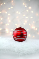 One Red Decorative Holiday Bulb with Silver Glitter sitting in Soft Fluffy Snow Vertical