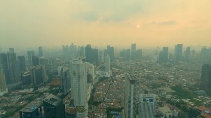 Fototapeta premium Time lapse city sunset through the glass. A beautiful urban panoramic cityscape from golden hour dusk to blue hour twilight. Sun setting and colours changing in the city centre of Jakarta, Indonesia.