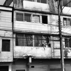 Very old apartments with windows with drying cloths and poles of lights and wires (in black and white)