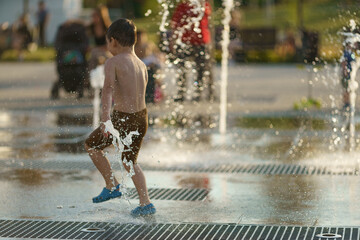 Child playing with water of fountain in the public Moscow park.