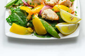 Cooked chicken breast pieces with peppers, sugar snap peas, and baby leaf spinach in a spicy sweet and sour sauce with fragrant rice