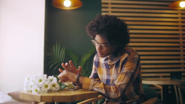 Excited young man waiting for girlfriend in restaurant checking time, first date