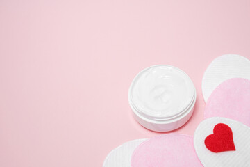 Obraz na płótnie Canvas A jar of thick cream and a heart on a pink background
