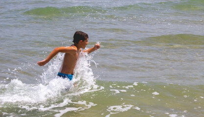 Boy running among the waves 