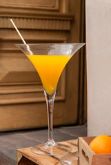 Orange drink in wineglass on background of wooden door