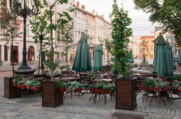 Fototapeta na wymiar Closed cafe restaurant with wood chairs, stacked upon tables outdoor in Lviv, Ukraine