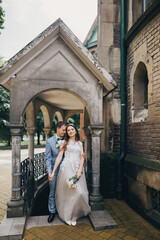 Beautiful sensual wedding couple gently hugging in european city. Provence wedding. Stylish bride and groom embracing on background of old church. Romantic moment