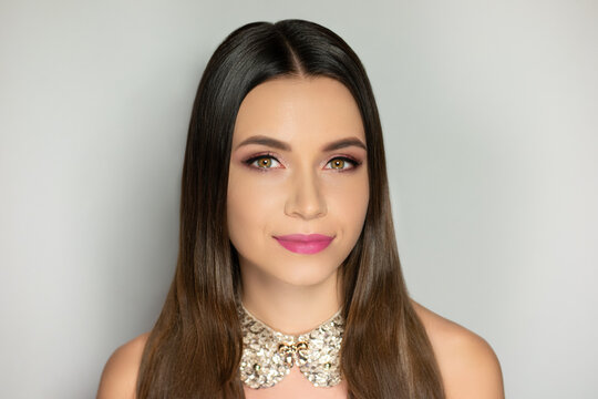 Beautiful woman skincare concept. Bright makeup with arrows shades shadows sequins. Evening hairstyle brunette long straight hair. background horizontal gray banner. New big necklace massive jewellery
