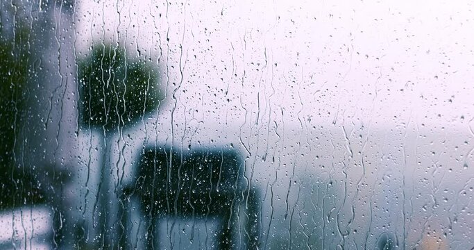 rain drops falling on the window glass at windy, rainy day