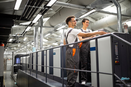 Print machine operators controlling printing process and quality control.