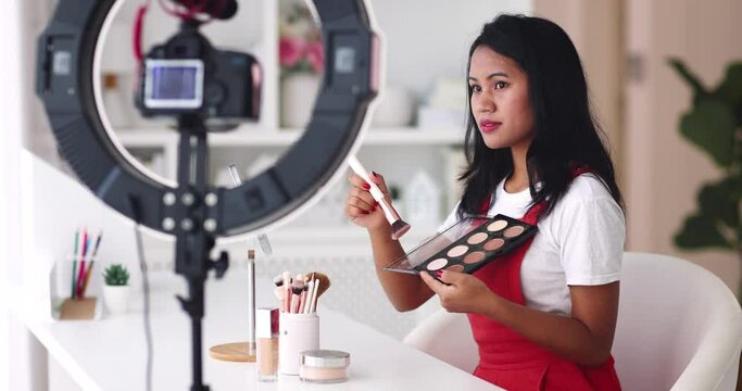 young asian woman streaming a beauty vlog from home, online content creator applying a makeup on, video tutorial
