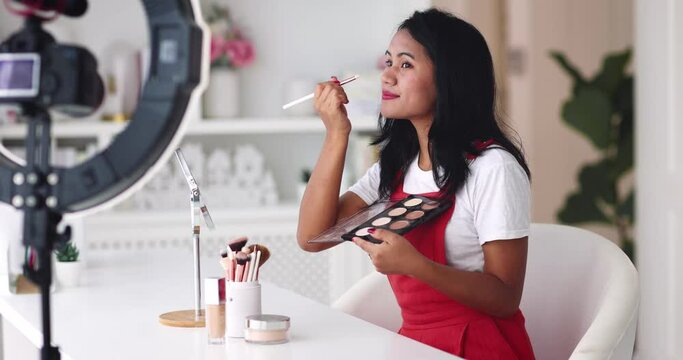 young asian woman streaming a beauty vlog from home, online content creator applying a makeup on, video tutorial