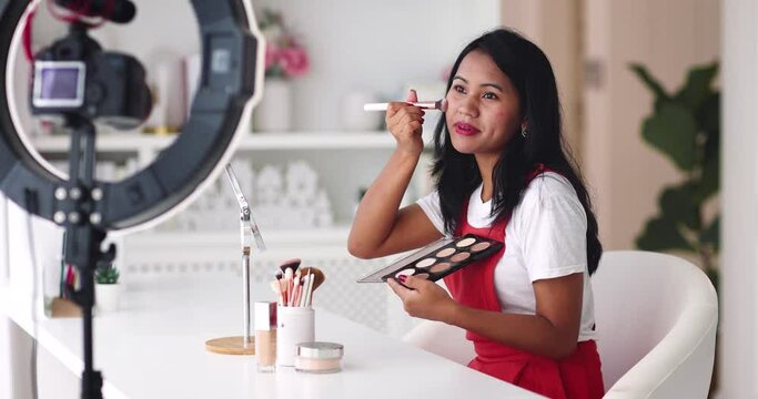 young asian woman streaming a beauty vlog from home, online content creator applying a makeup on, video tutorial