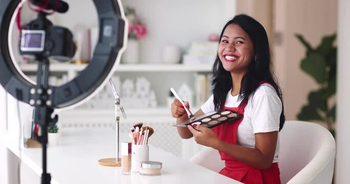 young asian woman streaming a beauty vlog from home, online content creator applying a makeup on, video tutorial