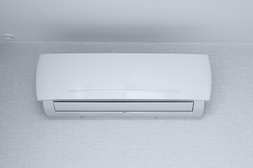 Air conditioner on  wall in the room against the background of white wallpaper.