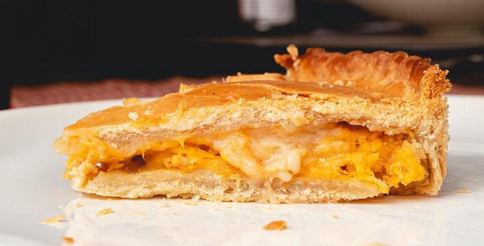 Fatia de torta de frango com requeij&atilde;o servida em um prato branco. Comida brasileira. Torta tradicional na cozinha brasileira para lanches e festas.