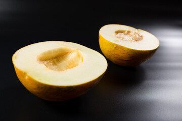 Melon cut in half. Aroma yellow melon on black. Halves of ripe melon.