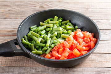 Sliced green beans and potamas in a frying pan for cooking lobio of green beans with vegetables and tomato. Step by step recipe