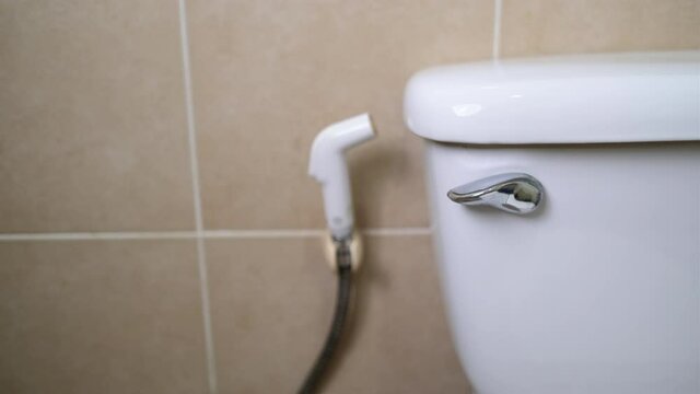 Close up hand push knob or button of toilet to flush water for cleaning in bathroom.