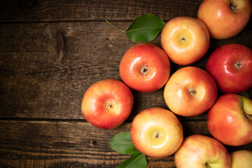 Red and yellow ripe apples lying on a wooden table in the form of a pyramid.Fresh bright fruits and berries on a wooden background.