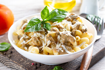 Pasta with spinach and cheese sauce on a light wooden background.