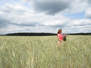 a girl in a dress goes into the field with her back