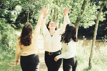 3 young woman laughing and clapping hands together in the forest, friendship and care concept