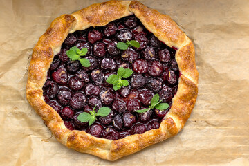Summer galette with cherries on brown concrete background