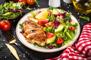 Healthy food concept. Grilled chicken with fresh salad at dark wooden table.