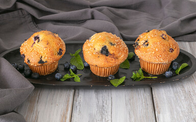 delicious muffins with blueberries on a wooden table. fresh berries and sweet pastries on the board. 