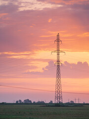 high voltage tower on field with beautiful sunset sly behind with copy space