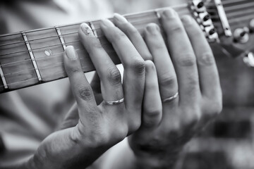 Mãos com aliança de noivado tocando violão