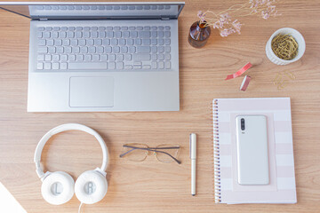 Minimalist office desk workspace with glasses, wallet, dried eucalyptus branch, golden paper clips on a wooden background. Flat lay, top view. Finances concept.