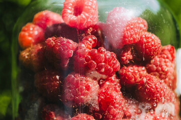 Ripe, red, fresh raspberries in a large glass jar. Fruit from the garden.