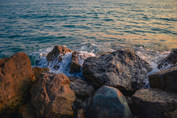 Fototapeta na wymiar Orange sunset on the beach with big stones. Large stones with a beautiful texture against the background of a sea sunset. Beautiful sunset over the Black Sea. 