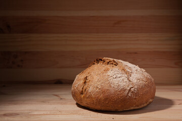Handmade fresh wheat bread on wooden background in the contrast light. horizontal frame side view with space area for text or design