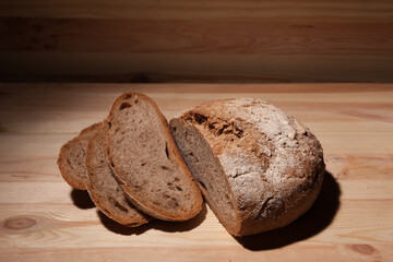 Fresh handmade wheat bread cut into pieces on wooden background in the contrast light. horizontal frame high angle view