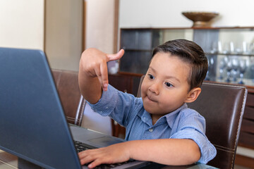 Four year old boy interacting with a laptop at home