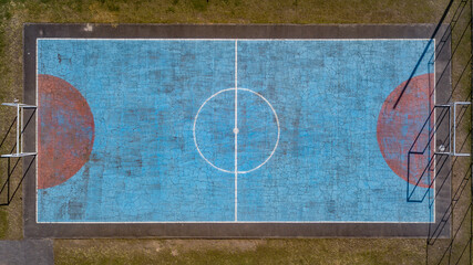 Multi-sport court with a central circle and a floor painted blue and weathered
