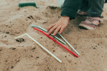 Kid picking up plastic garbage on the sand beach