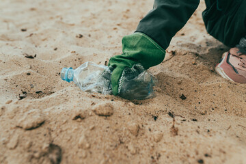 Kid picking up plastic garbage on the sand beach