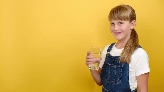 Healthy Cute School Girl Drinking Water, Isolated Over Yellow Background With Copy Space. Adorable Caucasian Child Hydrating Thirst To Prevent Dehydration. Children Health Care Nutrition Concept