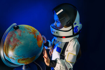 Teenager girl wearing astronaut costume and helmet studying the Earth globe