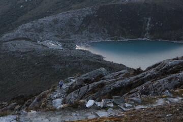 Mujer caminando en montaña junto a laguna
